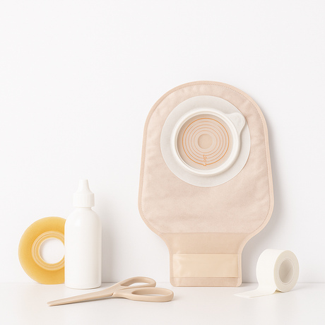 Ostomy supplies including an ostomy pouch, barrier ring, medical scissors, tape, and a skin prep bottle on a clean white background.